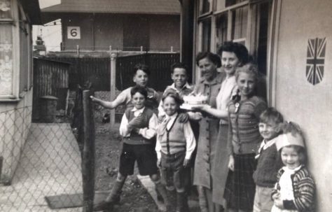 Family group outside a prefab decorated for the coronation, Albert Road, North Woolwich