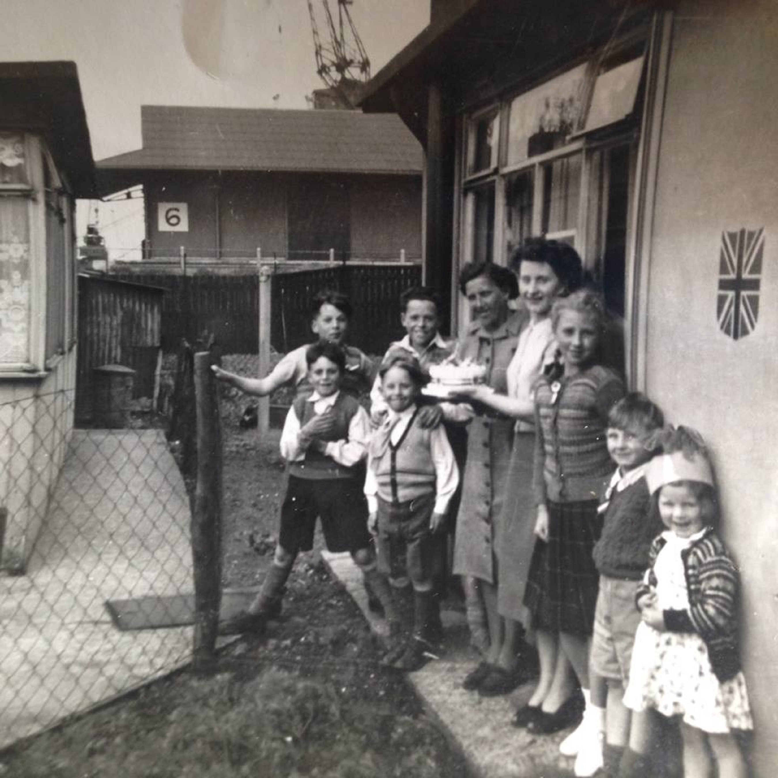 Family group outside a prefab decorated for the coronation, Albert Road, North Woolwich