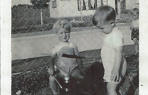 Two small children playing with buckets and spades in the prefab garden, Clement Road, Willesden