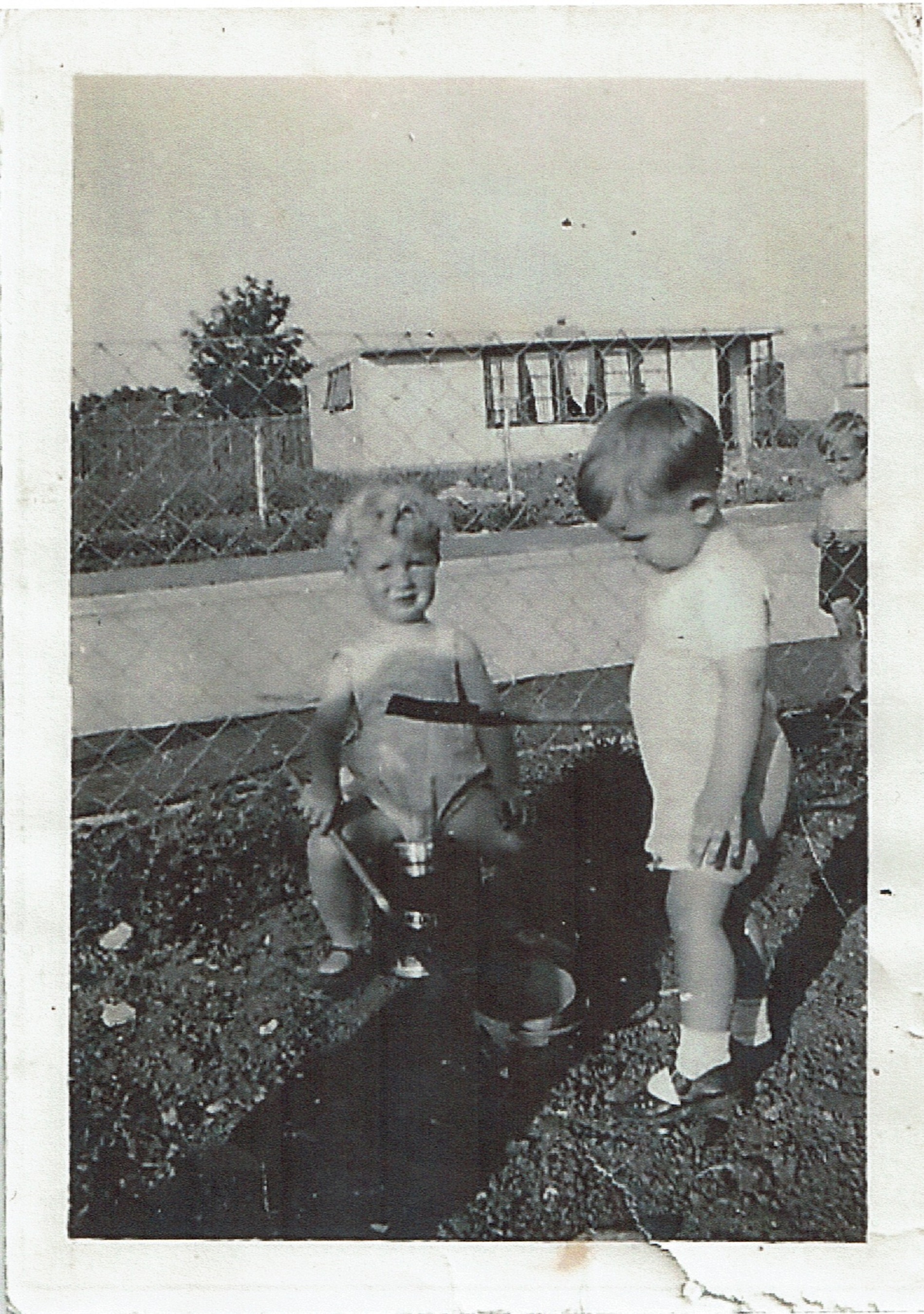Two small children playing with buckets and spades in the prefab garden, Clement Road, Willesden
