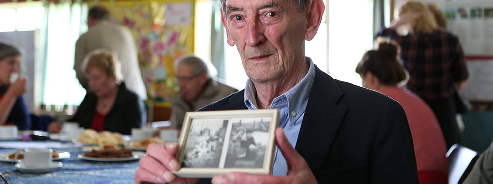 Ray Smith with photos of his prefab in Penarth