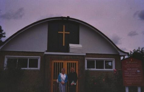 Photograph of a man and a woman, probably Alan's mum, from the Brine family in front of St Mark's Church, the "Prefab Church"