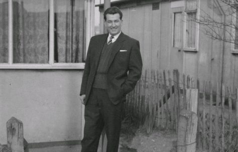 Man In suit standing in front of prefab.  Stewart Street, London E14