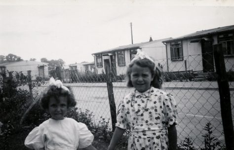Two little girls in a prefab front garden on the Harold Hill estate