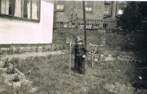 Alf with a big shovel and bike in the prefab garden at Narford Road, London E5