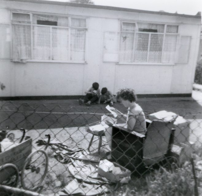 Woman and two boys in the garden of a prefab in Underhill Road, London SE22