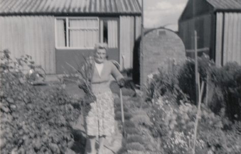Woman in prefab garden. Kedleston Gardens, Hainault