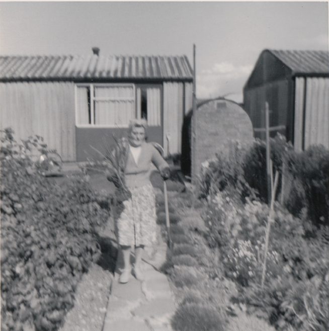 Woman in prefab garden. Kedleston Gardens, Hainault