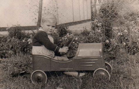 Boy racer. Ben in a toy car outside his prefab in Dartmouth Park Hill, London N19