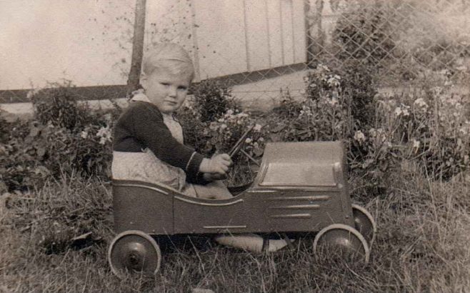 Boy racer. Ben in a toy car outside his prefab in Dartmouth Park Hill, London N19