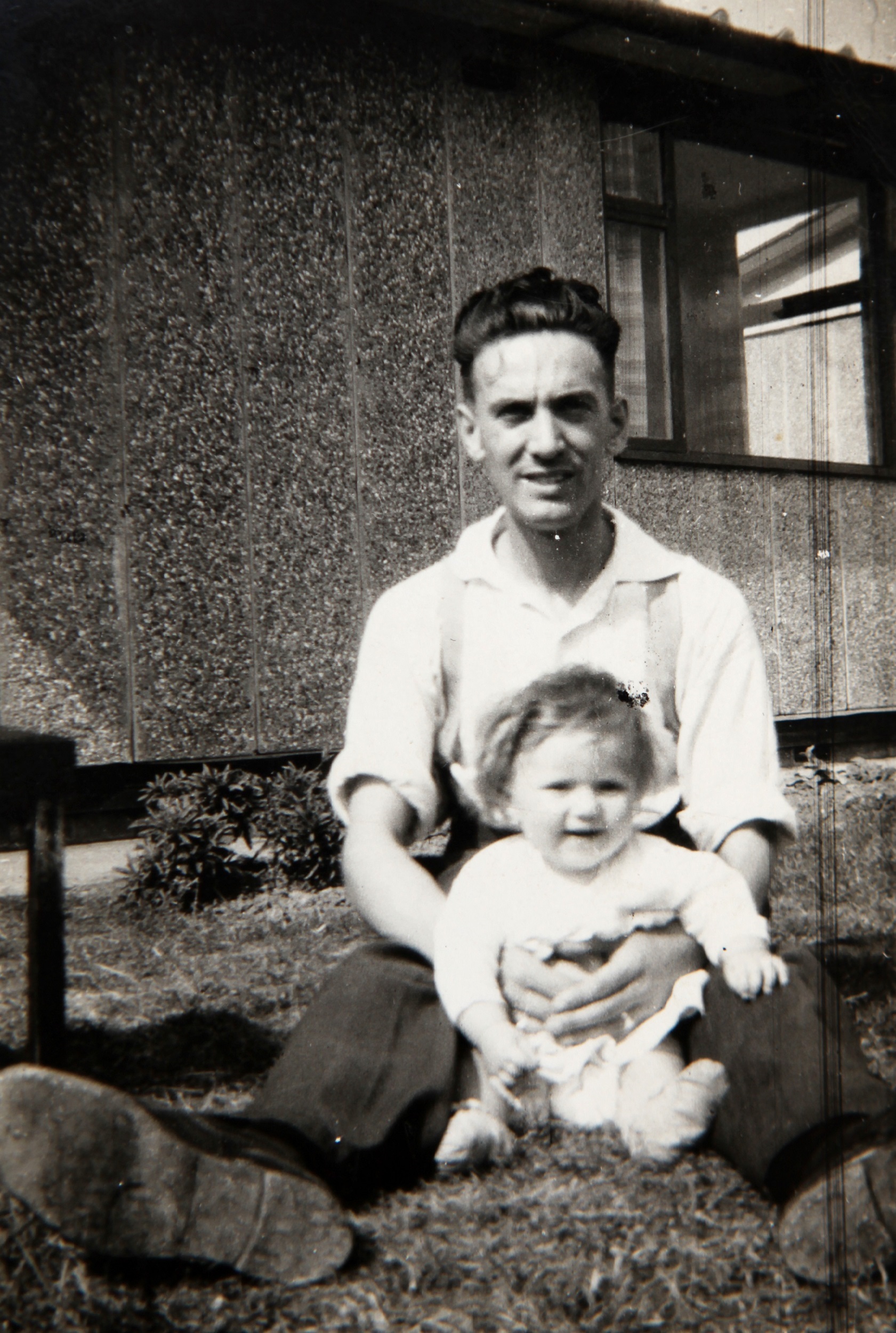 Dad with baby outside Tarran prefab. Bolsover, Derbyshire