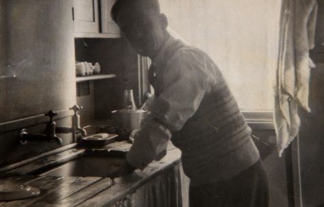 Dad washing up in prefab kitchen. Bolsover, Derbyshire