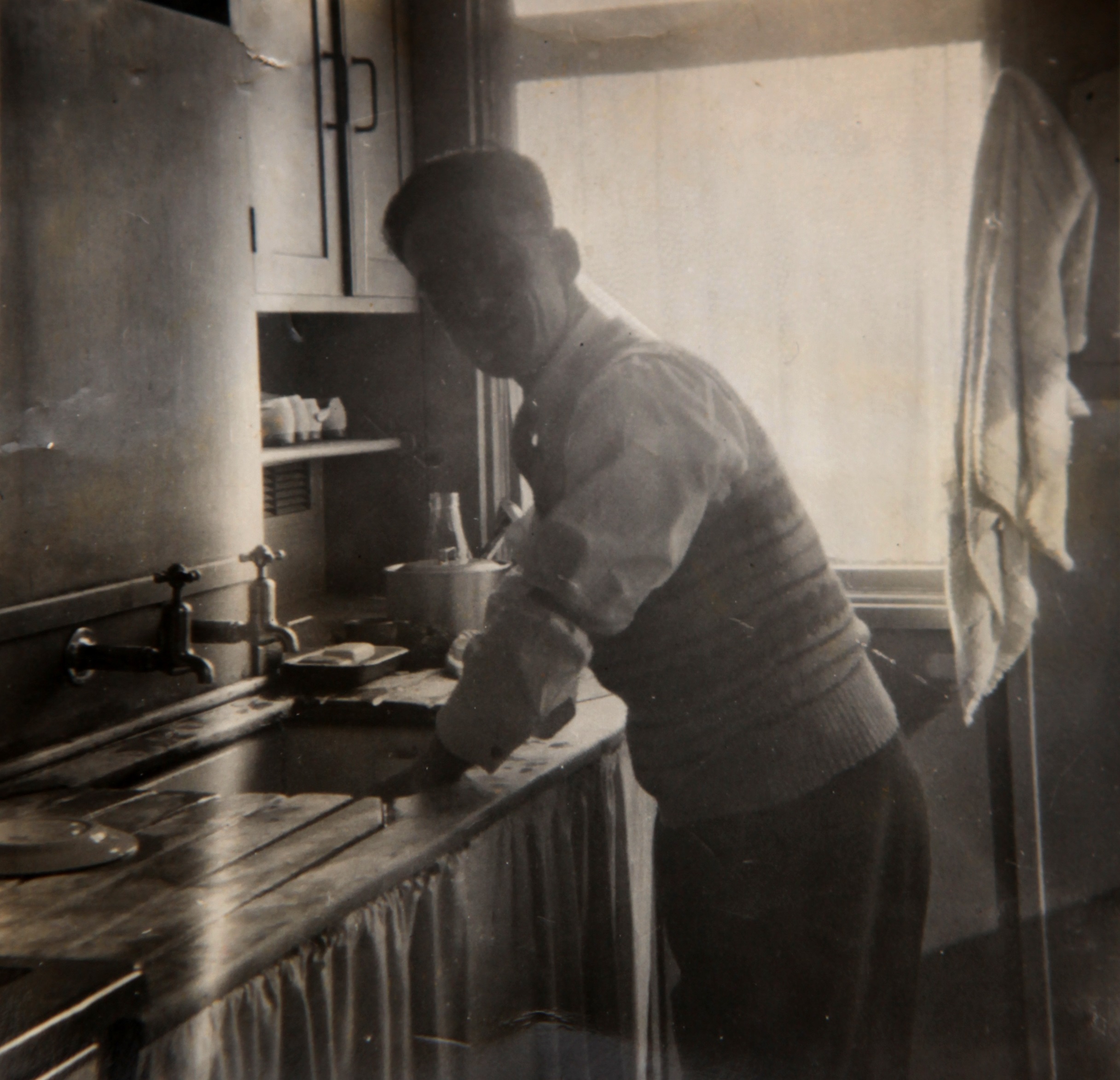 Dad washing up in prefab kitchen. Bolsover, Derbyshire