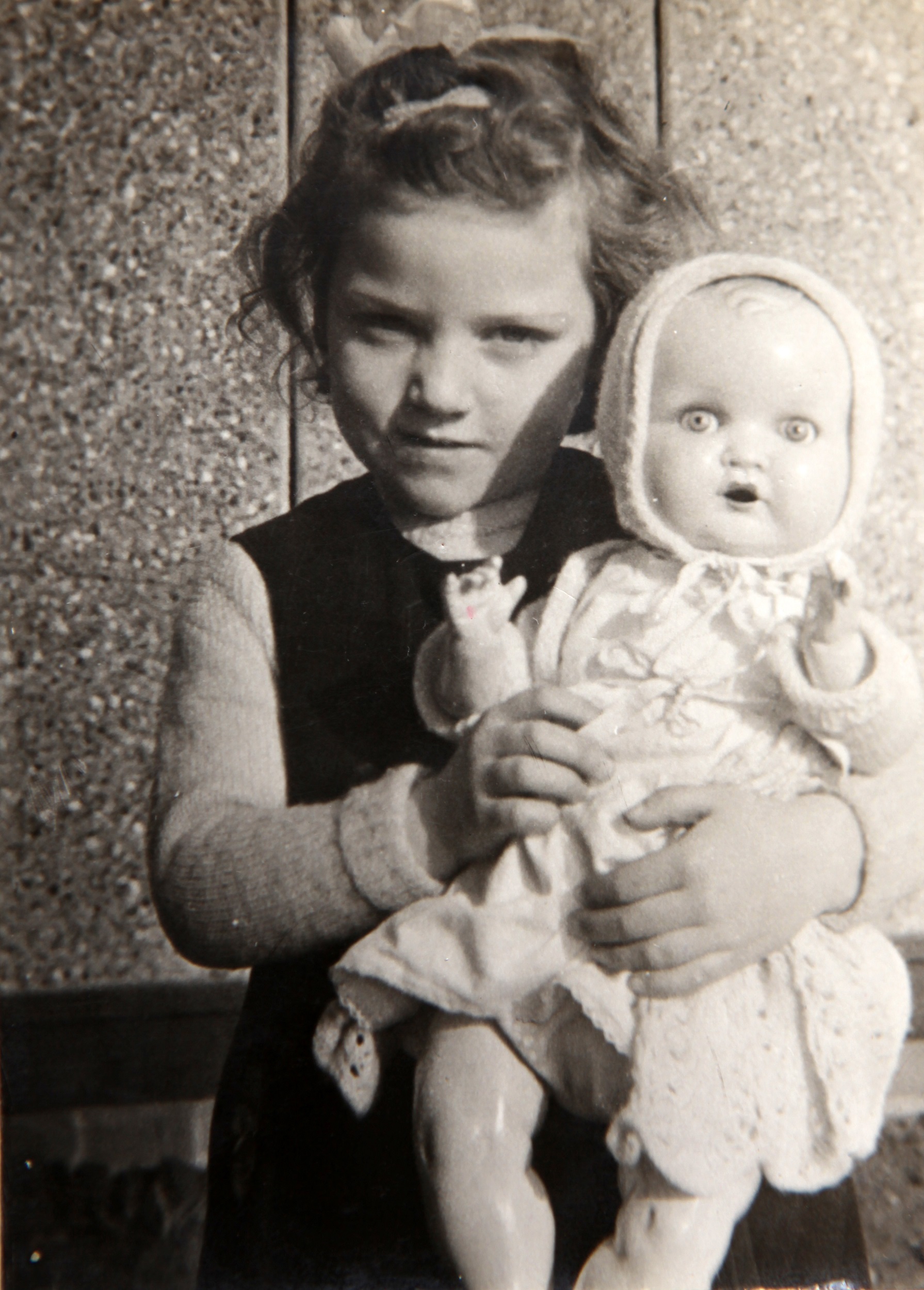 Pat holding her doll in the prefab kitchen. Bolsover, Derbyshire