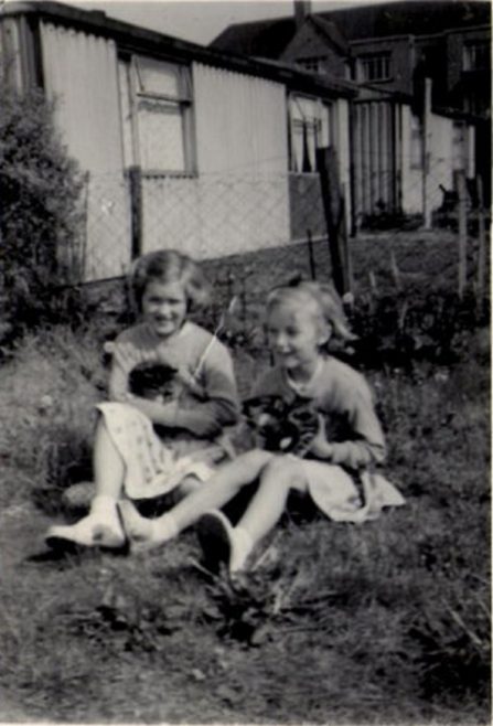 Two girls with kittens in the prefab garden. Hollyhedge bungalows, Blackheath, London SE3 | Brenda Anderson Browne