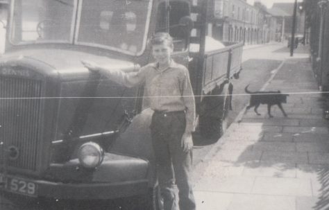 Older brother Harry in Tooke St standing outside our prefab which is out of view to the right. Another prefab(one of four here) is visible through the windscreen of the lorry.