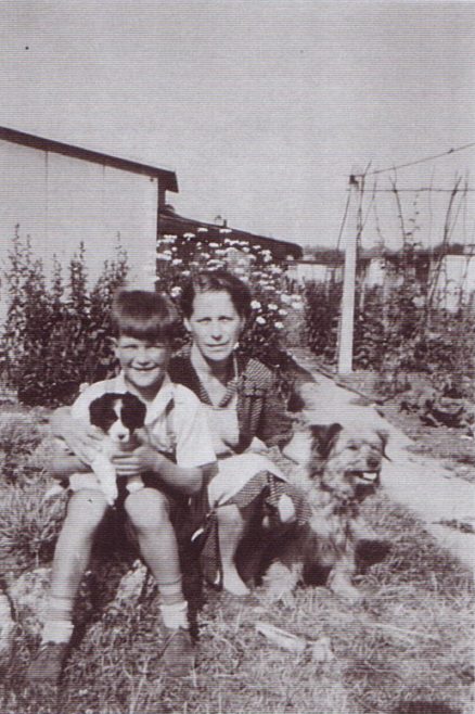 Jim and his mum with two dogs, runner bean canes in the background. Excalibur Estate, London SE6