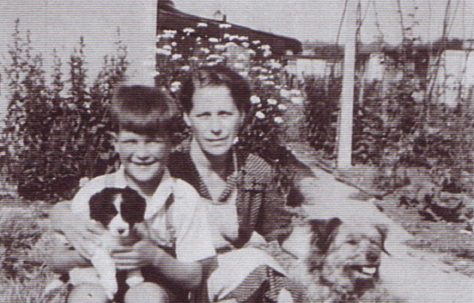 Jim and his mum with two dogs, runner bean canes in the background. Excalibur Estate, London SE6