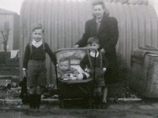 Mum and we three boys, posing outside the Anderson shelter. This would have been in 1948, judging by my physical size in the pram. To the left is the back of a house in Richmond Avenue. Mum and we three boys, posing outside the Anderson shelter. This would have been in 1948, judging by my physical size in the pram. To the left is the back of a house in Richmond Avenue. | Ray Watts
