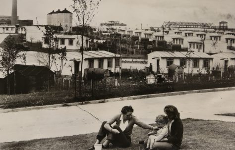 Overlooking the atomic town, family members sit on lawn near their prefabricated houses. 19/7/1948, Harwell, England